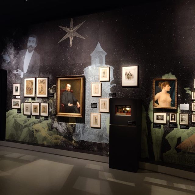Cimaise d'exposition Méliès avec portraits, gravures et illustrations encadrées sur fond étoilé