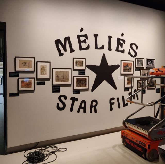 Mur scénographié avec logo Méliès Star Film peint et gravures anciennes encadrées
