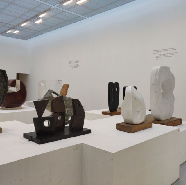 Salle d'exposition de sculptures modernes en pierre et bronze sur socles blancs