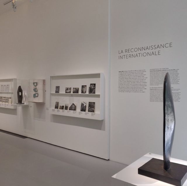 Salle d'exposition avec texte mural La Reconnaissance internationale, vitrines et sculpture sur socle