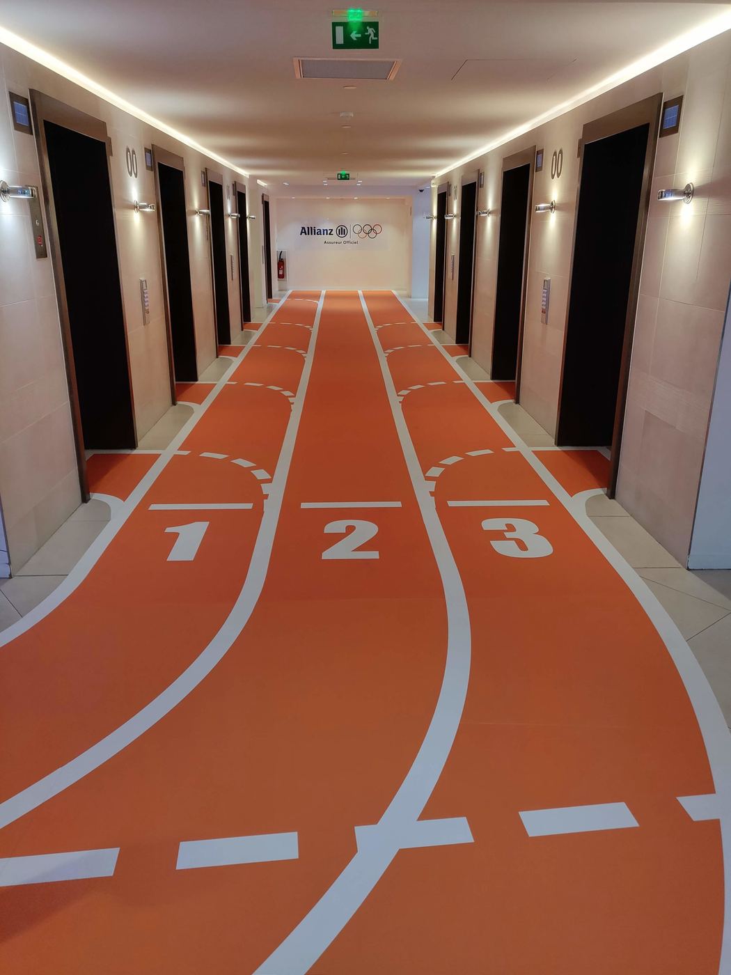 Sol imprimé façon piste d'athlétisme dans un couloir d'hôtel partenaire Allianz JO